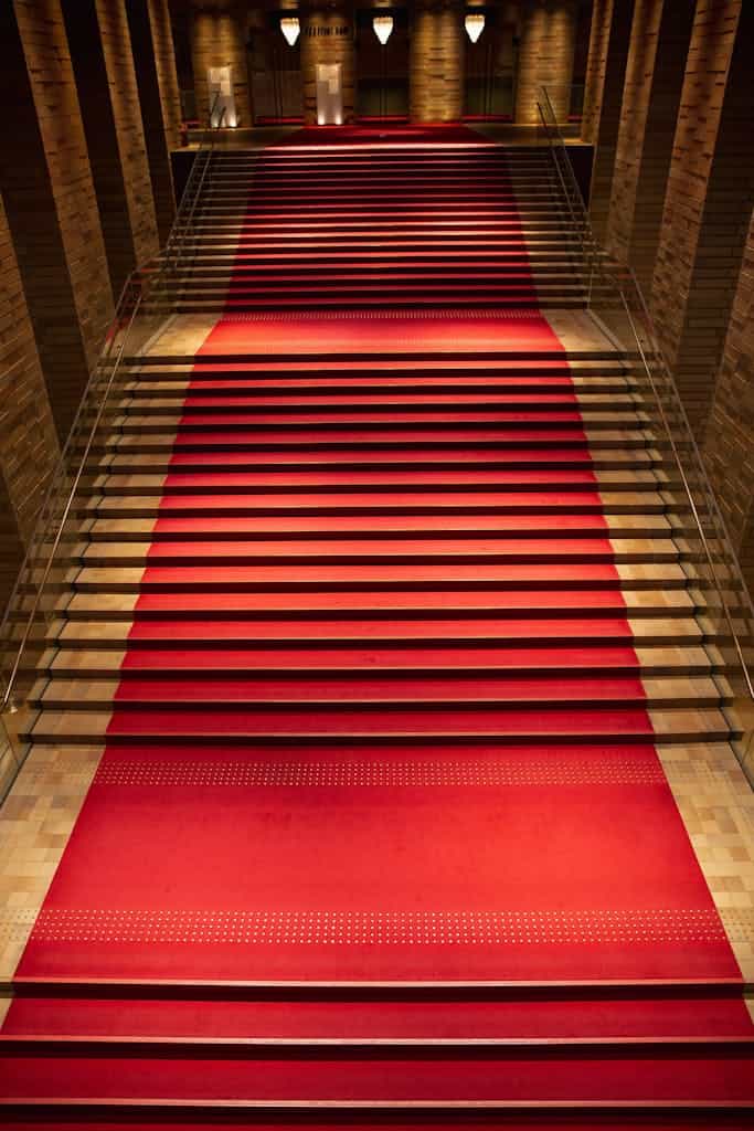 From above of majestic rich interior of old building hall with red carpet on staircase