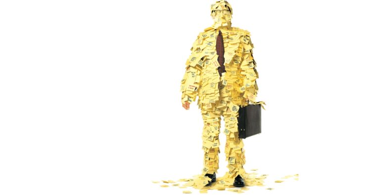 Humor på jobben Person kledd i dress dekket av Post-it lapper, symboliserer kreativitet og motivasjon på arbeidsplassen.